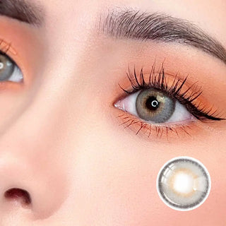 Zoomed-in view of a model wearing Say Yes Spotlight Gray lenses, emphasizing their delicate gray tones paired with warm makeup accents.